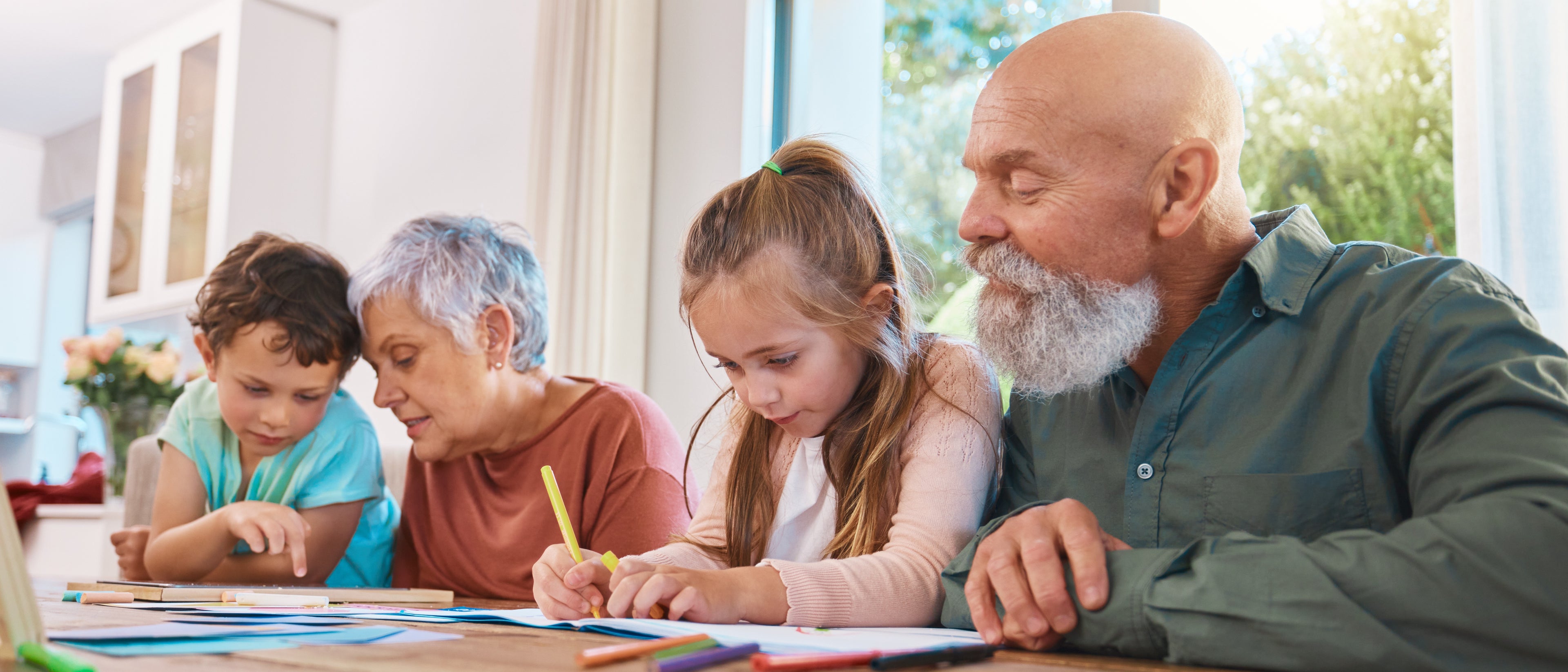 Grandparents and grandchildren sitting together in a home setting, engaging in an activity.